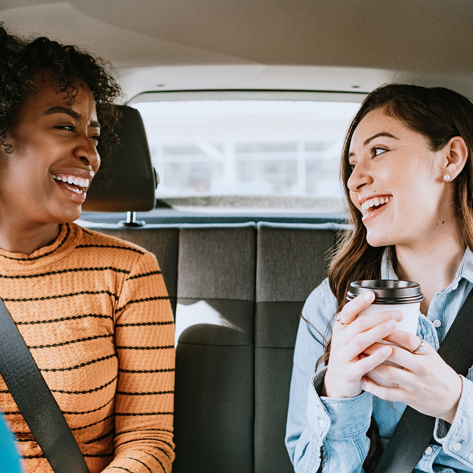 Two friends ride in a crowdsourced taxi, having requested a pick up and drop off on a smartphone.  Shot in Los Angeles, California.